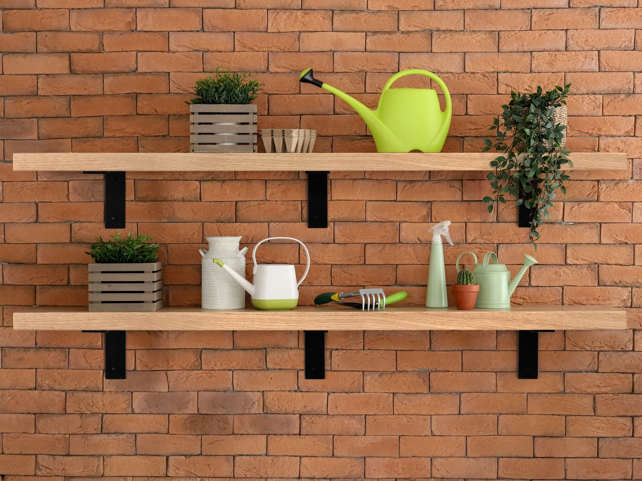 Oak wooden shelves with visible L brackets with gardening tools against a brick wall
